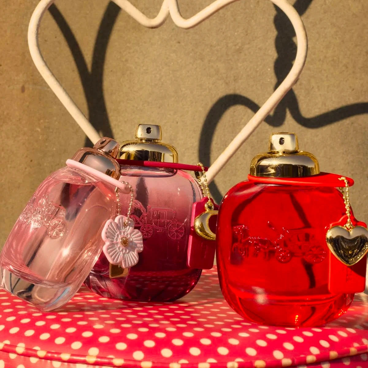 Refect Beauty Coach Love for Women perfume bottles in pink and red glass with gold caps and decorative charms