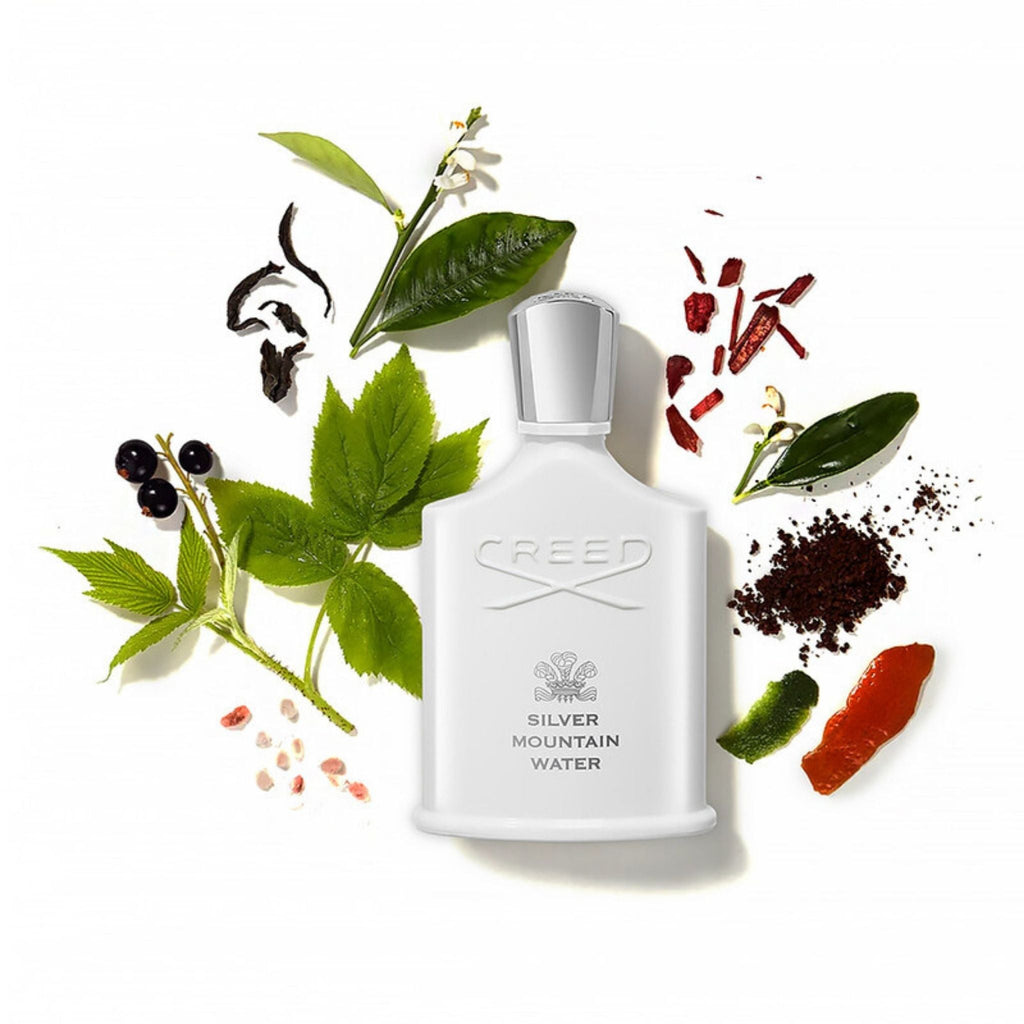 Refect Beauty Creed Silver Mountain Water perfume bottle surrounded by fresh green tea leaves, blackcurrants, and citrus
