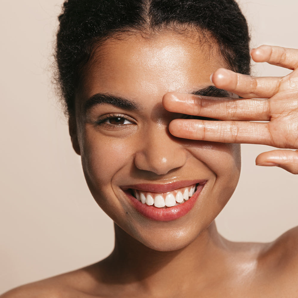 Refect Beauty Dermactive Acti-Solaire SPF 50+ tinted fluid on a smiling woman with glowing, healthy skin