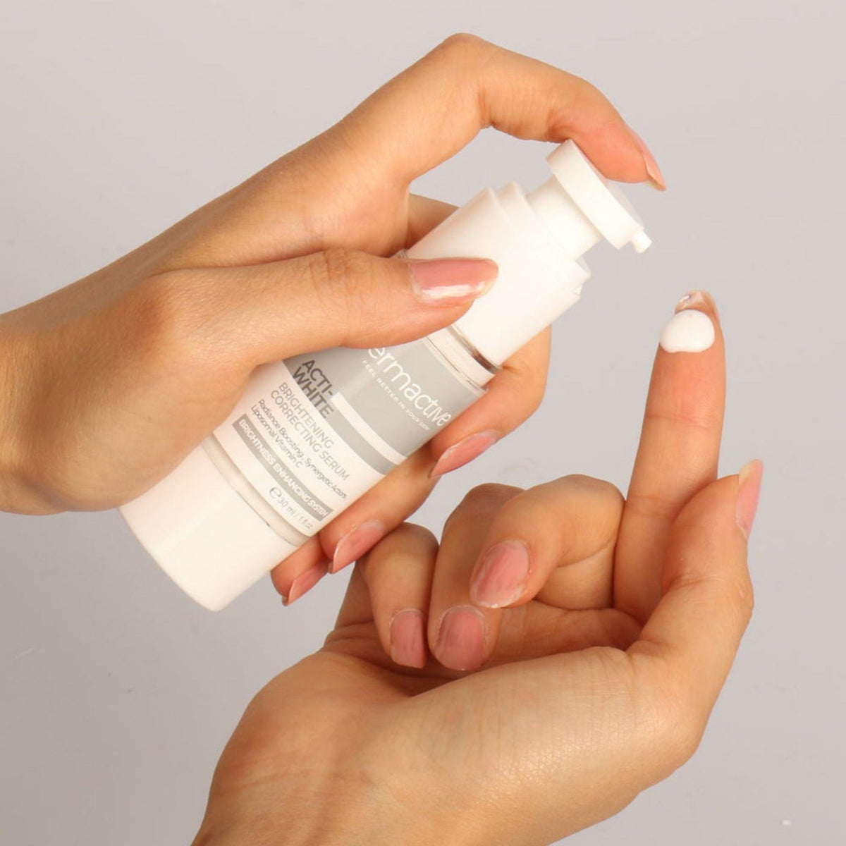 Refect Beauty Dermactive Acti-White brightening serum bottle with a drop of white cream on a finger for application.