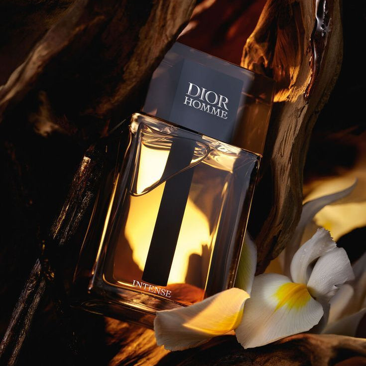 Refect Beauty Dior Homme Intense Eau de Parfum bottle surrounded by iris flowers and dark wood in warm lighting