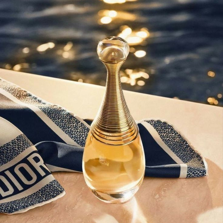 Refect Beauty Dior J'adore Eau de Parfum in its iconic gold-necked glass bottle resting on a blue and white towel.