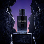 Refect Beauty Dior Sauvage Parfum bottle displayed on a dark stone pedestal against a twilight sky and rock formations.
