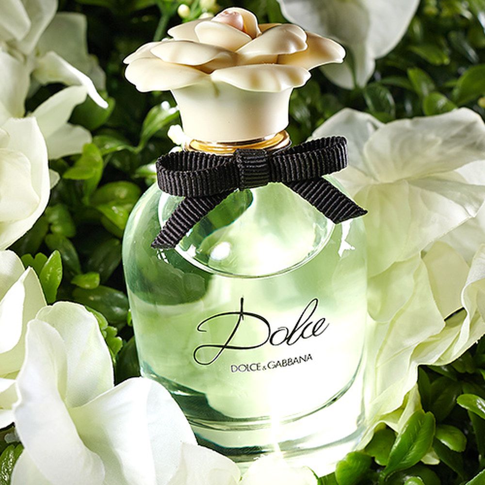 Refect Beauty Dolce & Gabbana Dolce Eau de Parfum bottle with a floral cap nestled among white flowers and greenery.