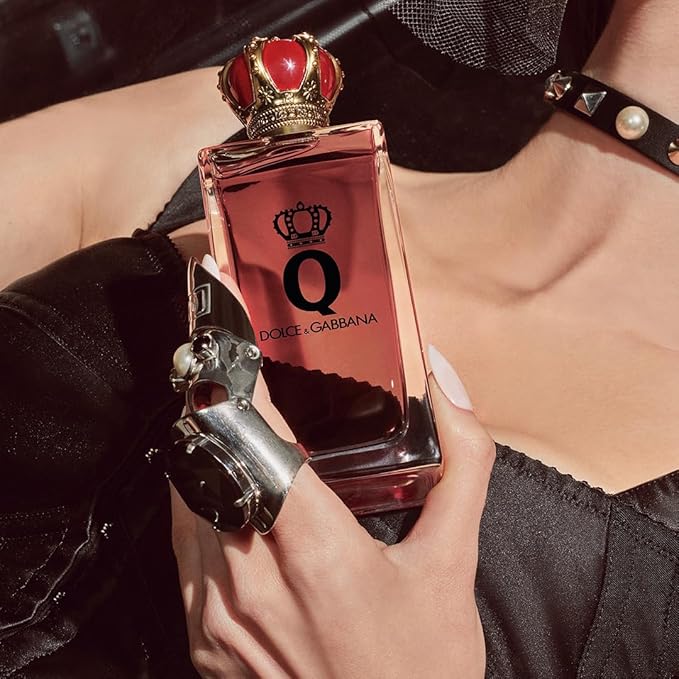Refect Beauty Dolce & Gabbana Q Eau de Parfum bottle with a red crown cap held by a woman in a black outfit