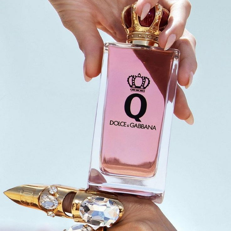 Refect Beauty Dolce & Gabbana Q Eau de Parfum in a glass bottle with a gold crown cap held by a hand with rings