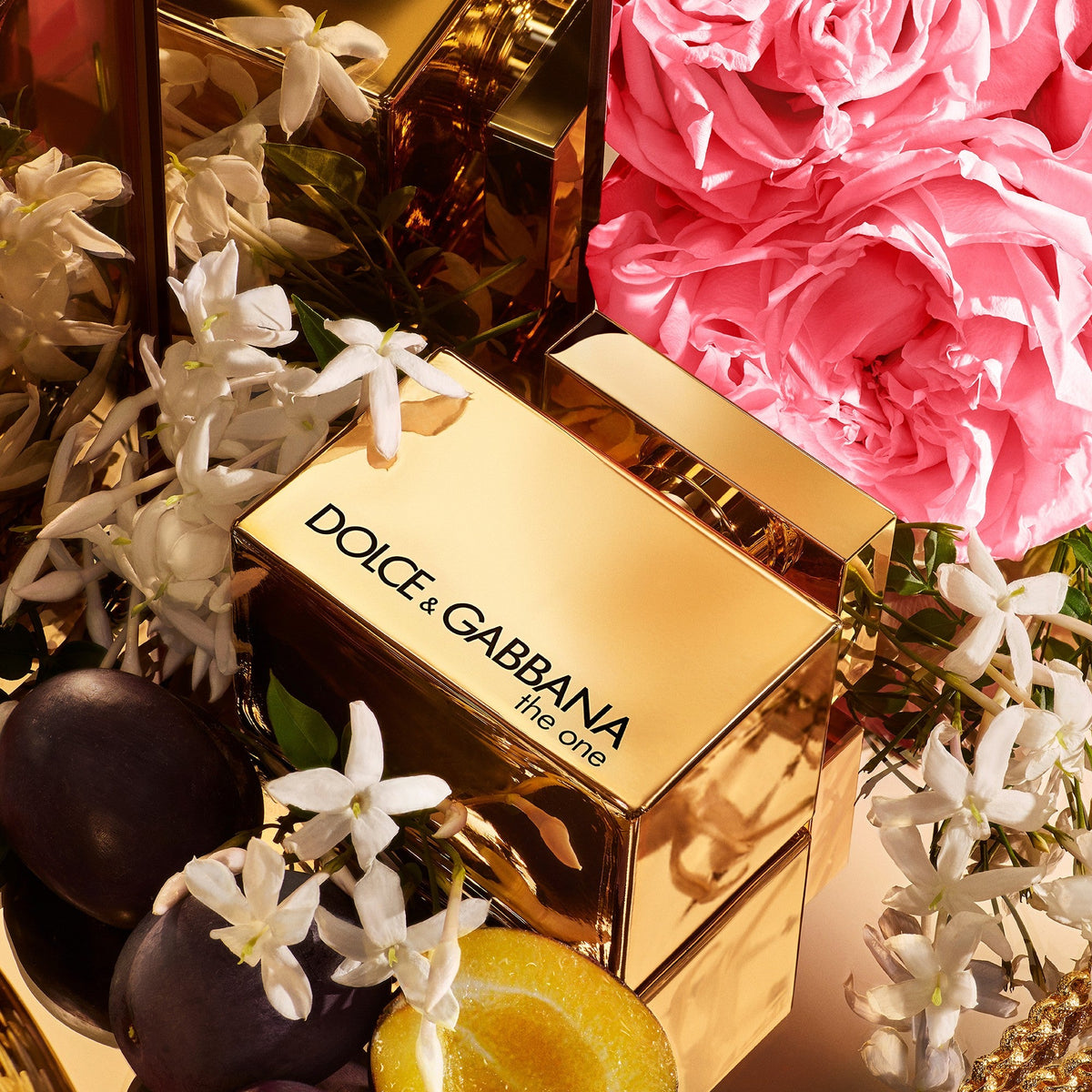 Refect Beauty Dolce & Gabbana The One Gold perfume bottle surrounded by fresh jasmine flowers, pink roses, and fruit.