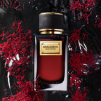 Refect Beauty Dolce & Gabbana Velvet Zafferano perfume bottle surrounded by red saffron threads on a dark wet surface.