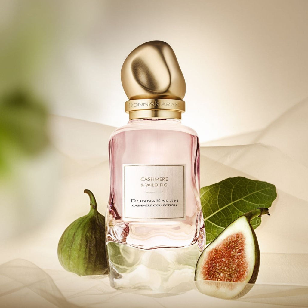 Refect Beauty Donna Karan Cashmere & Wild Fig Eau de Parfum bottle with gold cap, fresh figs, and soft fabric backdrop