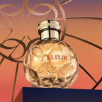 Refect Beauty Elie Saab Elixir Eau de Parfum in a round glass bottle with gold cap against a sunset gradient backdrop