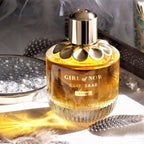 Refect Beauty Elie Saab Girl Of Now Shine eau de parfum in a gold-accented glass bottle on a reflective surface.