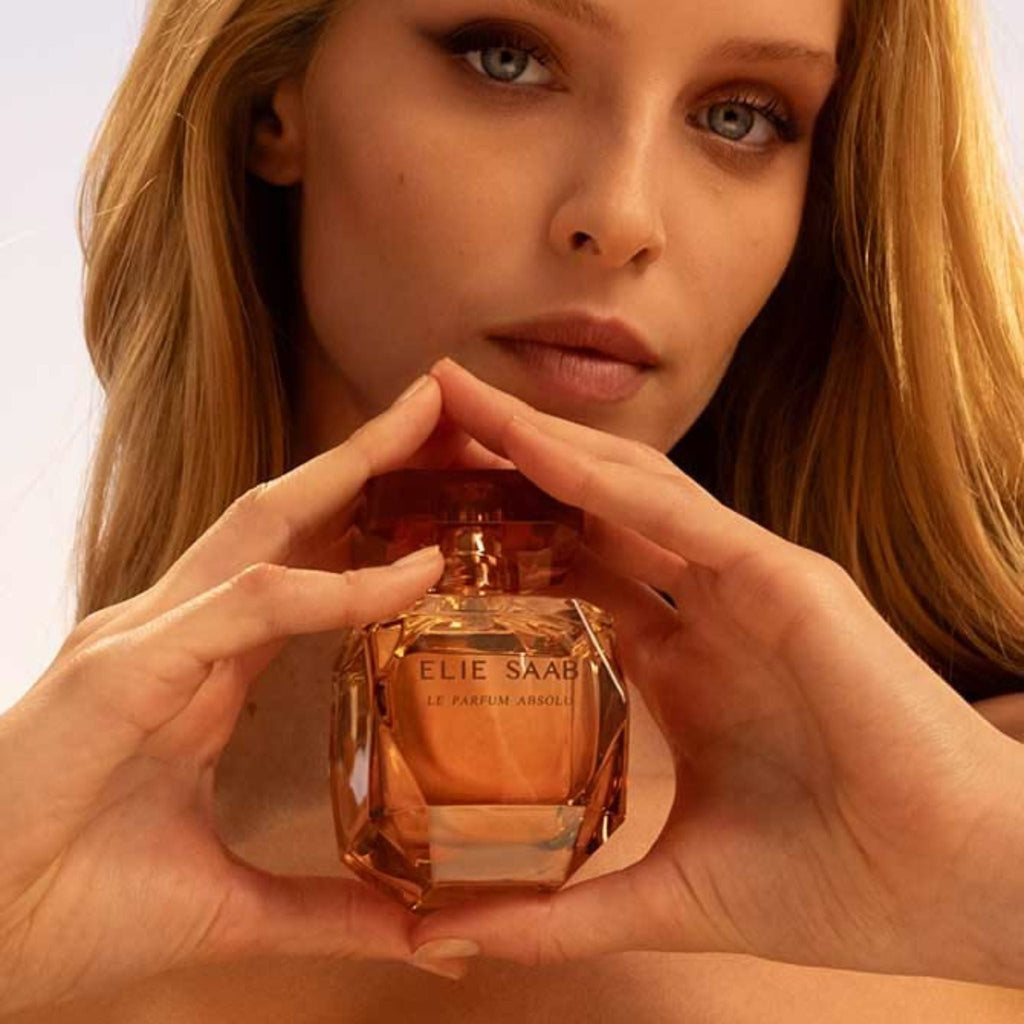 Refect Beauty Elie Saab Le Parfum Absolu perfume bottle held by a woman with a warm amber glow
