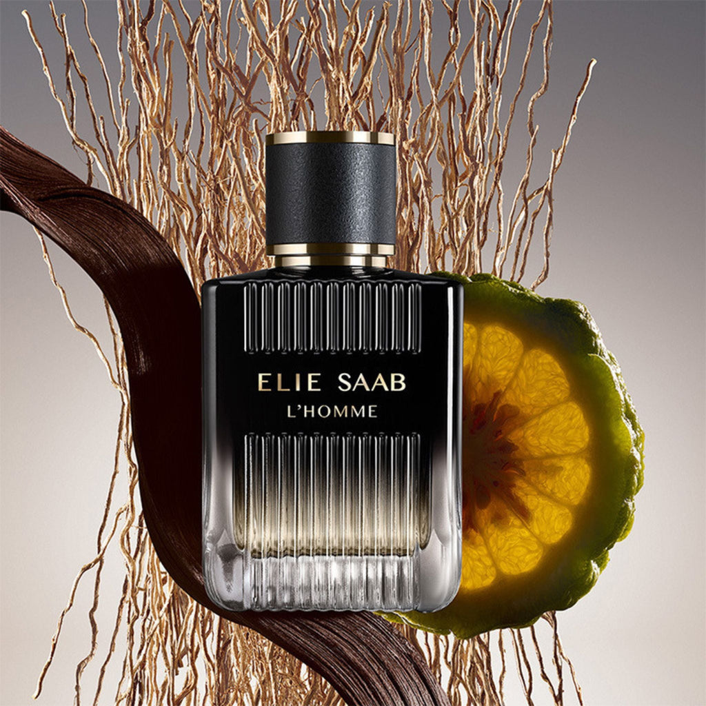 Refect Beauty Elie Saab L'Homme Eau de Parfum bottle with bergamot and vetiver roots on a neutral background