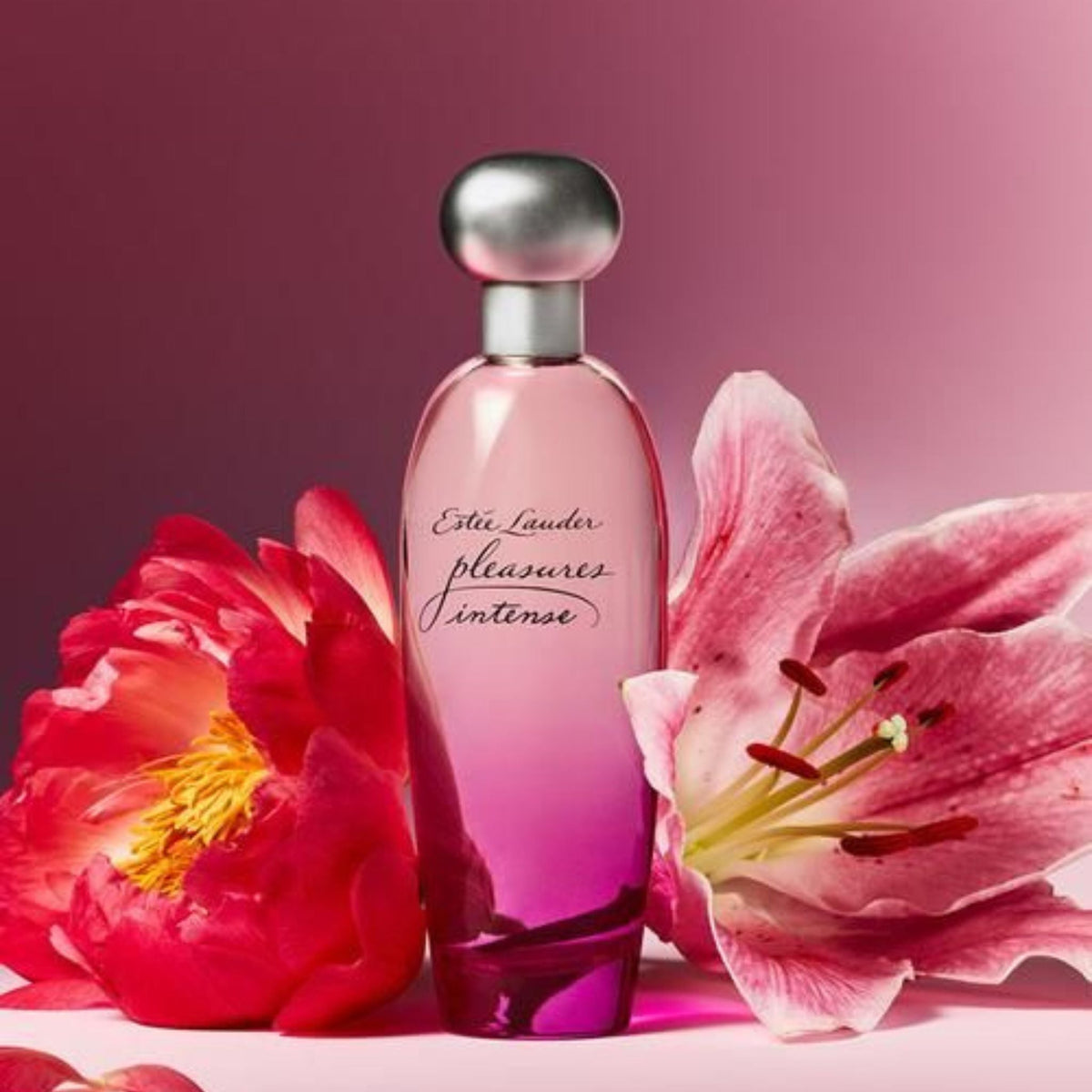 Refect Beauty Estée Lauder Pleasures Intense Eau de Parfum bottle surrounded by vibrant pink peony and lily flowers.
