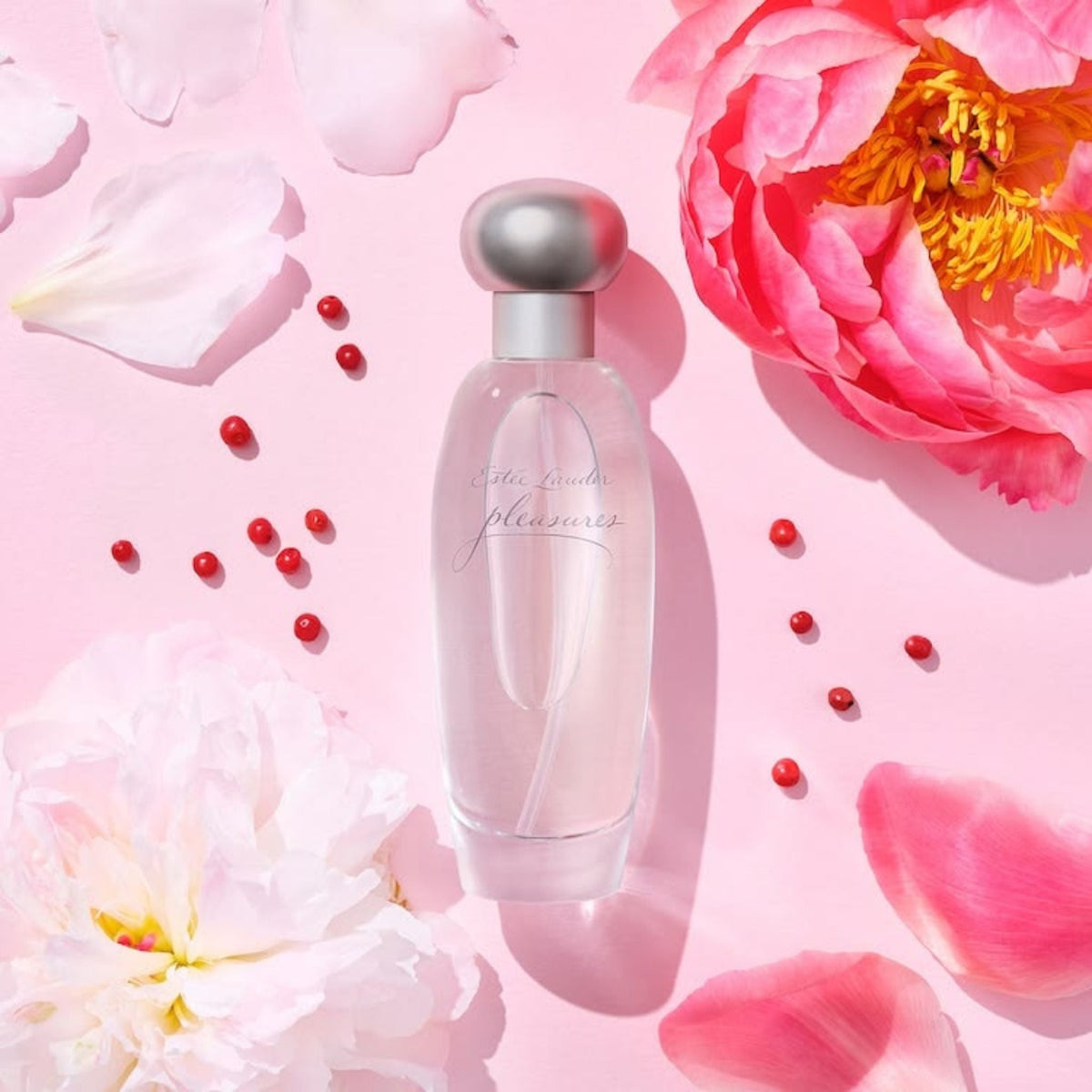 Refect Beauty Estée Lauder Pleasures Eau de Parfum bottle surrounded by pink peony petals and small red berries.