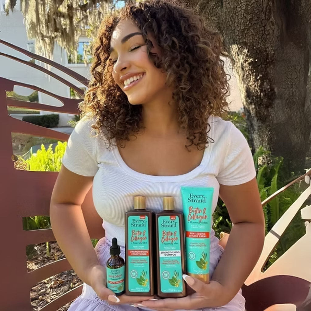 Refect Beauty model smiling while holding Every Strand Biotin, Collagen & Rosemary Mint hair care products outdoors.