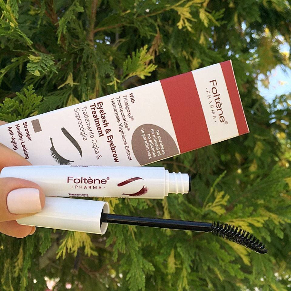 Refect Beauty Foltene Eyelash & Eyebrow Treatment box and white applicator wand held against a green foliage background