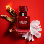 Refect Beauty Givenchy L'Interdit Rouge perfume bottle with burning wood and white flower on a vibrant red background