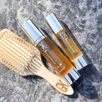 Refect Beauty GK Hair Argan Oil Serum bottles and a wooden hair brush on a stone surface