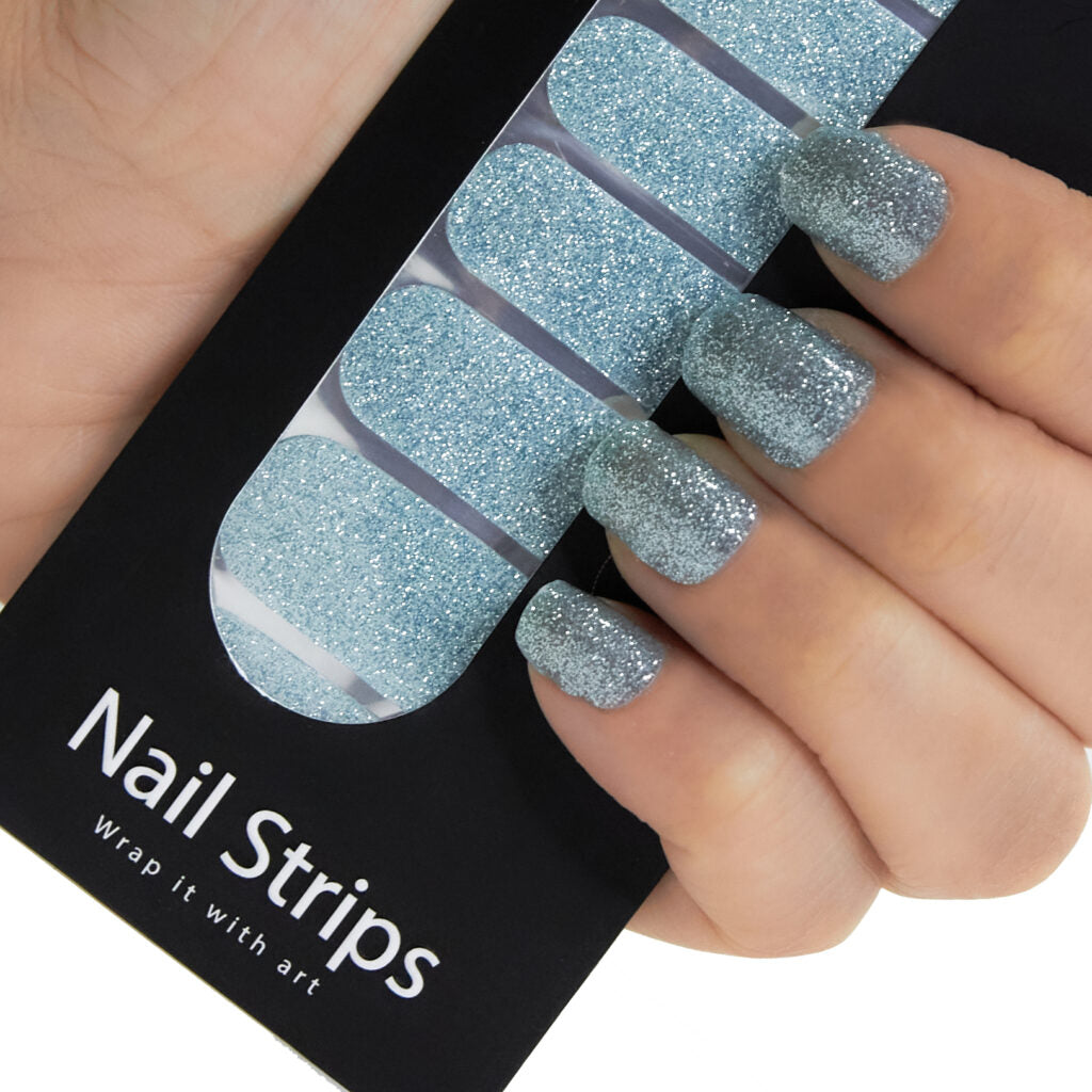 Refect Beauty Yolo nail strips featuring a sparkling light blue glitter finish applied to a model's fingernails. Main image