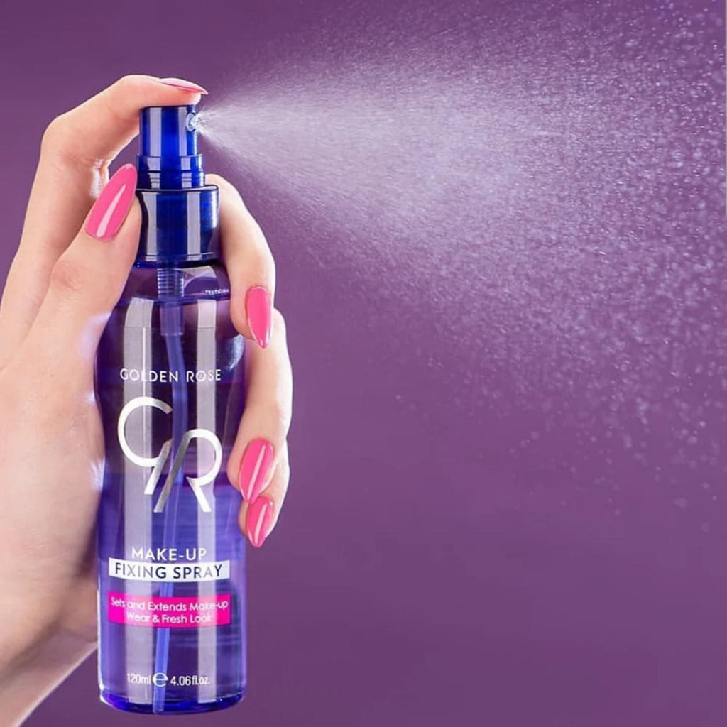 Refect Beauty Golden Rose Makeup Fixing Spray being misted from a blue bottle held by a hand with pink nails