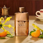 Refect Beauty Gucci Guilty Pour Femme Intense perfume bottle in metallic gold, surrounded by mandarin and flowers.