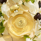 Refect Beauty Guess Bella Vita Eau De Parfum bottle surrounded by white flowers and cherries on a golden background