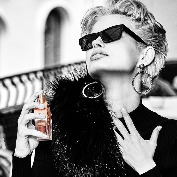 Refect Beauty model wearing sunglasses applying Guess Bella Vita Rose Eau de Toilette on her neck in a chic setting