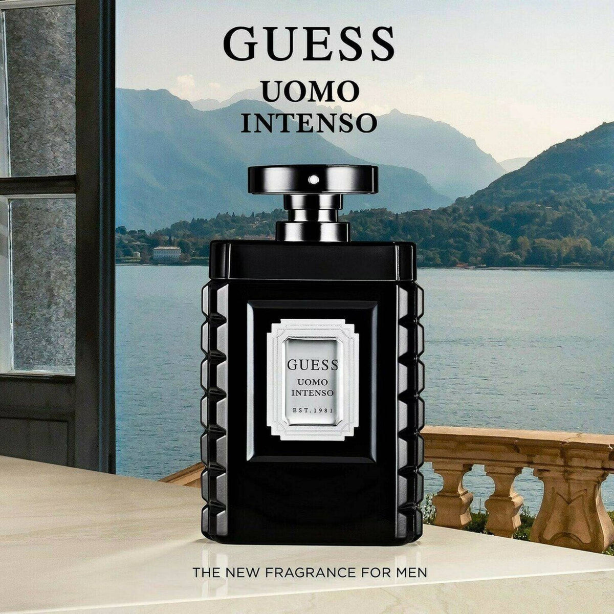 Refect Beauty Guess Uomo Intenso Eau de Parfum in a sleek black bottle against a scenic lake and mountain backdrop.