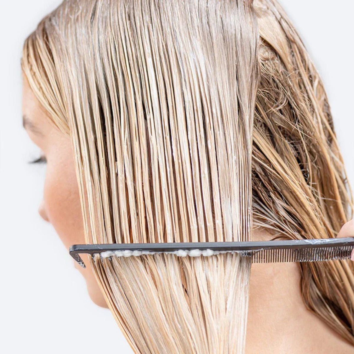 Refect Beauty Hair Burst conditioner applied to wet blonde hair being detangled with a black comb