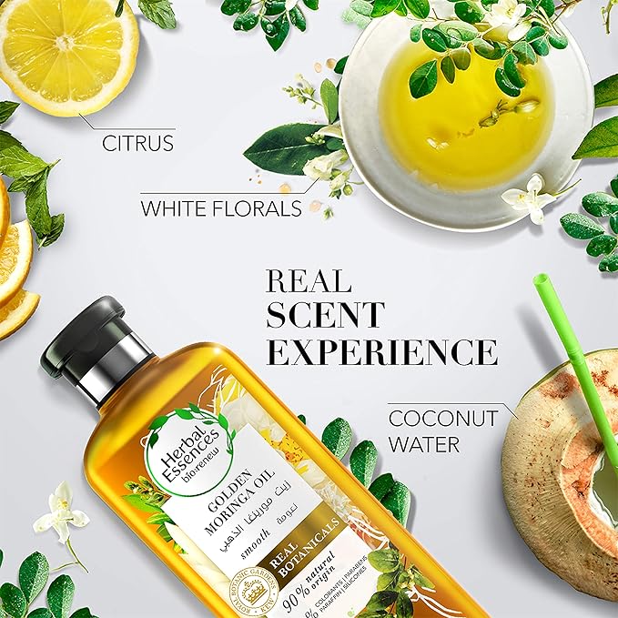 Refect Beauty Herbal Essences Golden Moringa Oil conditioner bottle surrounded by citrus, white flowers, and coconut.