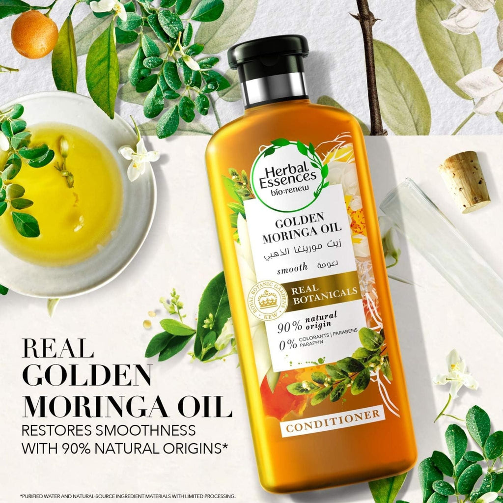 Refect Beauty Herbal Essences Golden Moringa Oil conditioner bottle surrounded by fresh botanicals and orange slices.