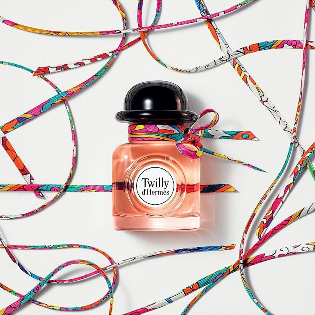 Refect Beauty Hermès Twilly d’Hermès perfume bottle with a black cap and a colourful silk ribbon tied around the neck.