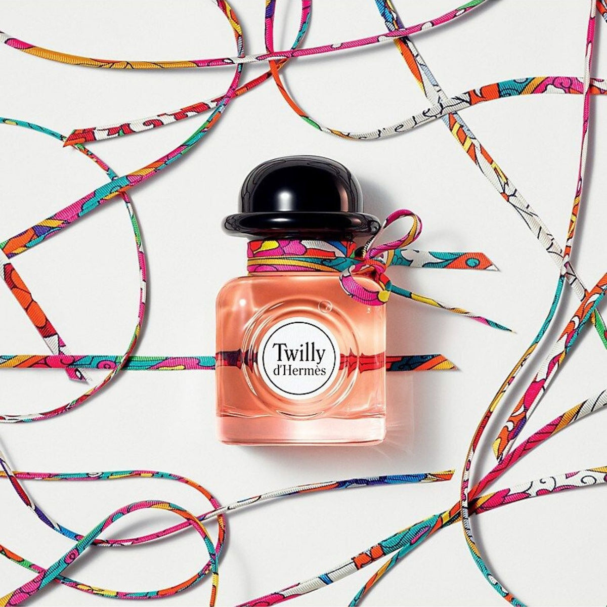 Refect Beauty Hermès Twilly d’Hermès perfume bottle with a black cap and a colourful silk ribbon tied around the neck.