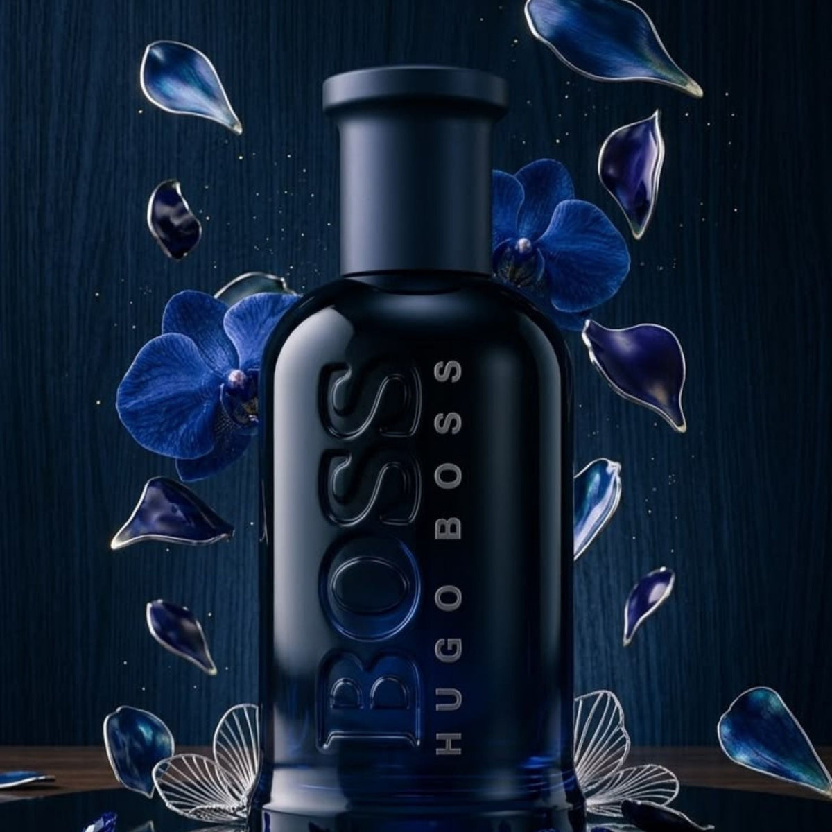 Refect Beauty Hugo Boss Bottled Night Eau de Toilette in a dark blue glass bottle surrounded by blue orchid petals.