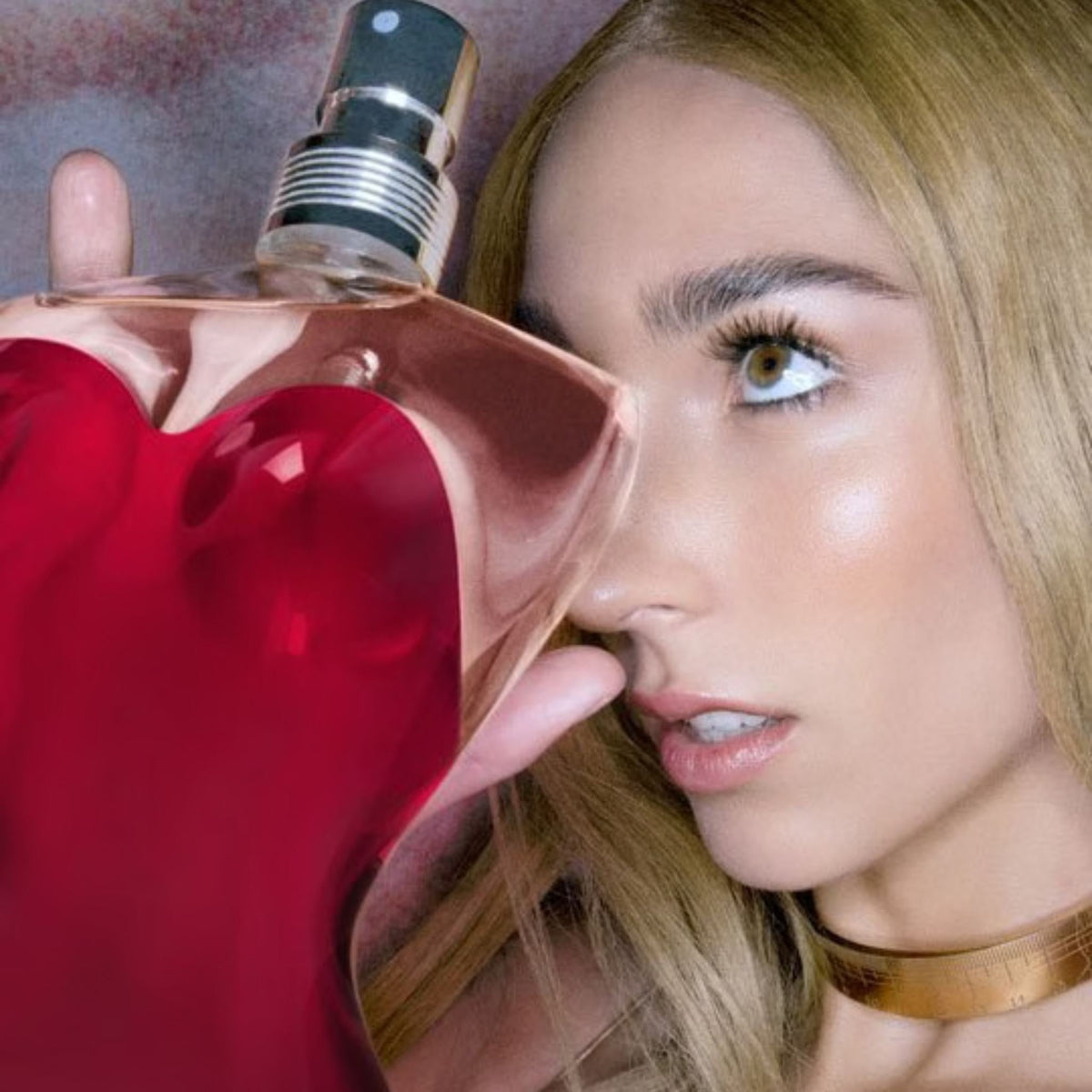 Refect Beauty model holding a Jean Paul Gaultier Classique perfume bottle with a red corset-shaped glass design