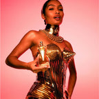 Refect Beauty Jean Paul Gaultier Divine perfume bottle held by a model in a gold metallic corset against a pink background