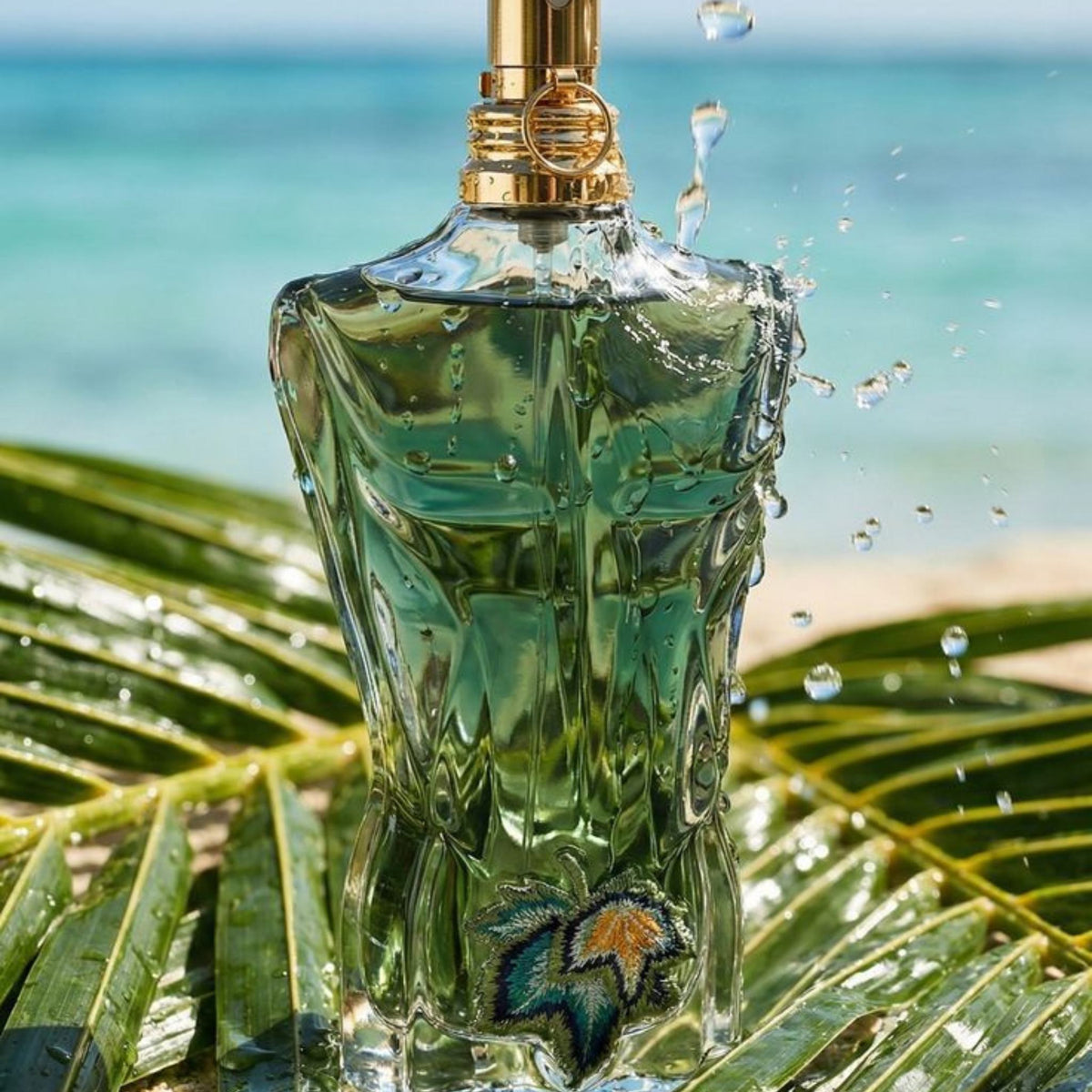 Refect Beauty Jean Paul Gaultier Le Beau Paradise Garden perfume bottle with tropical leaf embroidery on a beach