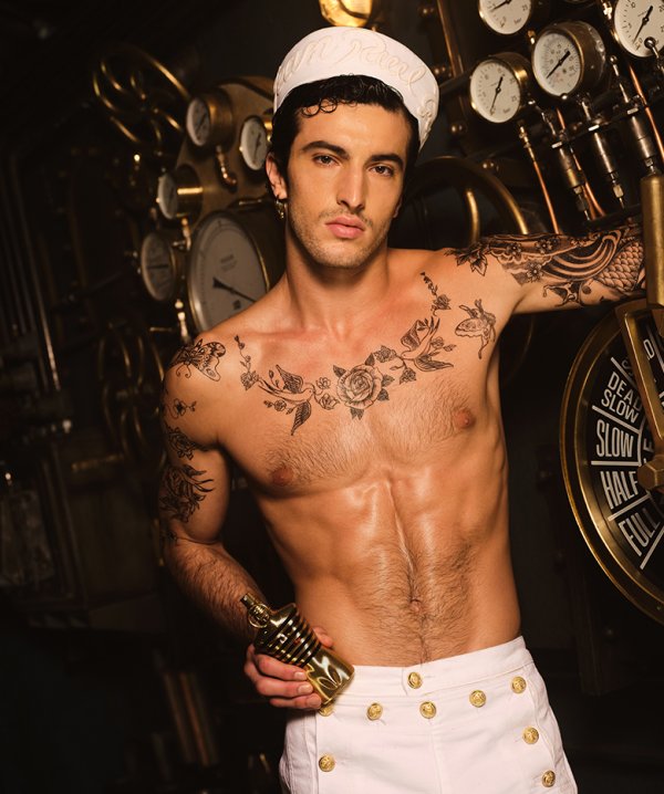 Refect Beauty model posing with Jean Paul Gaultier Le Male Elixir gold bottle in a nautical-themed setting