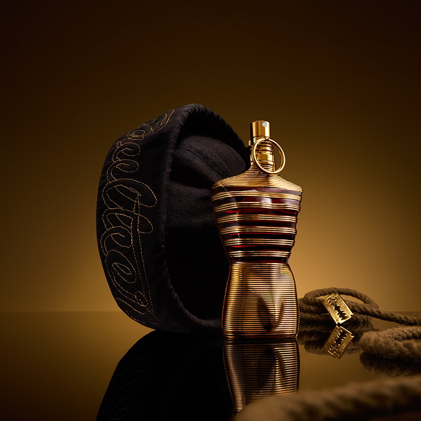 Refect Beauty Jean Paul Gaultier Le Male Elixir perfume bottle with gold stripes next to a black sailor cap and rope