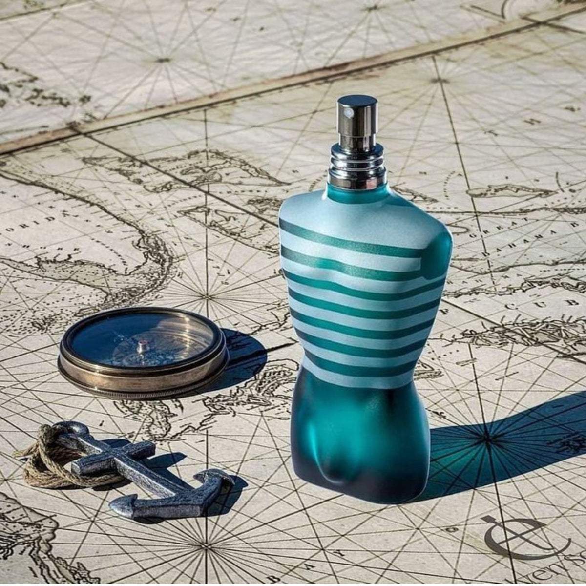 Refect Beauty Jean Paul Gaultier Le Male torso-shaped perfume bottle on a vintage nautical map with a compass and anchor