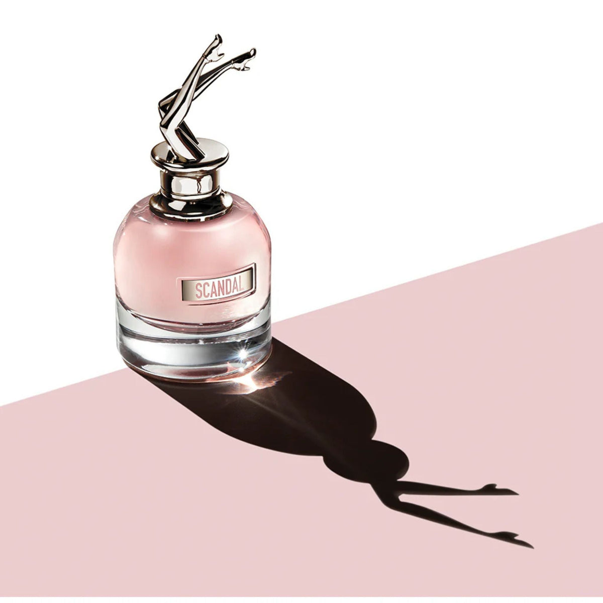 Refect Beauty Jean Paul Gaultier Scandal perfume bottle with iconic legs cap casting a dramatic shadow on pink surface