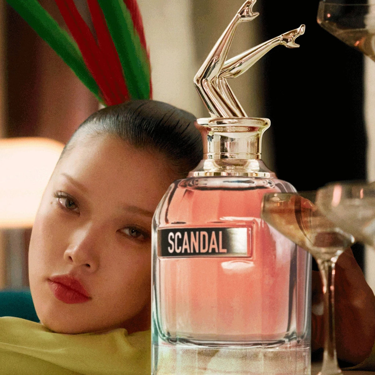 Refect Beauty Jean Paul Gaultier Scandal perfume bottle with iconic gold legs cap next to a model in a chic setting