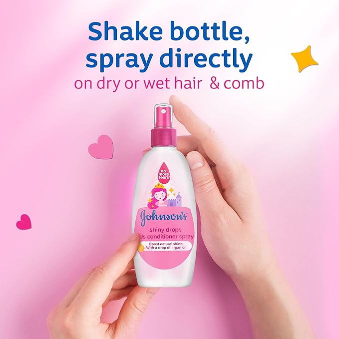 Refect Beauty Johnsons Kids Shiny Drops spray conditioner bottle held in hands against a pink background
