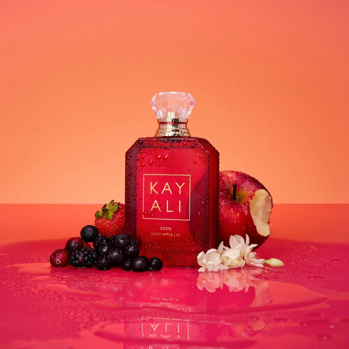 Refect Beauty Kayali Eden Juicy Apple 01 perfume bottle surrounded by fresh red apples, berries, and white flowers.