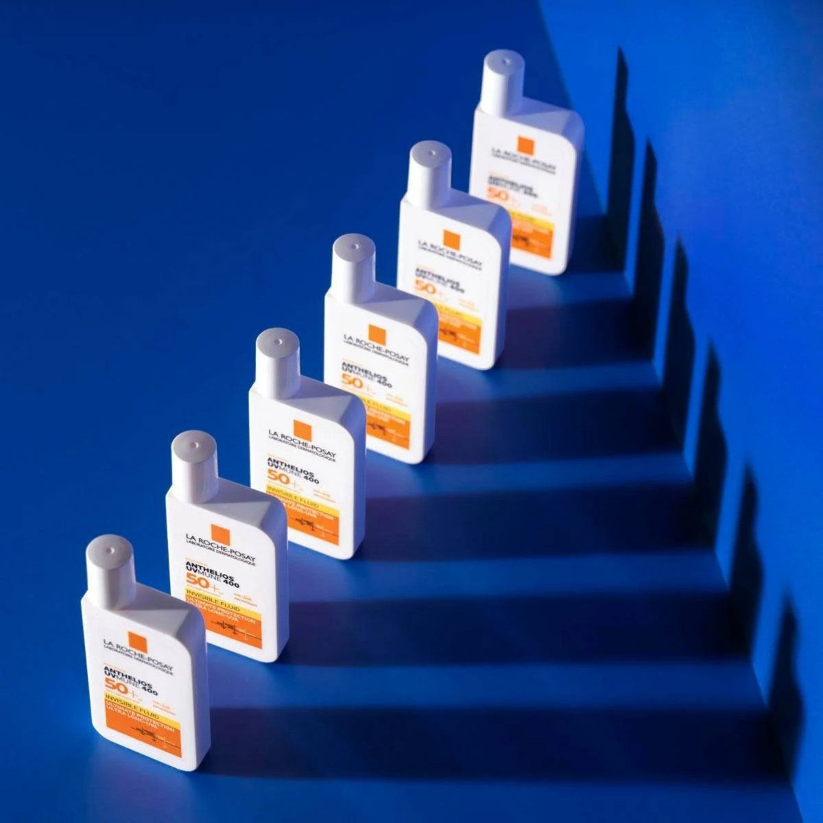 Refect Beauty La Roche-Posay Anthelios Uvmune 400 SPF50+ invisible fluid sunscreen bottles on a blue background