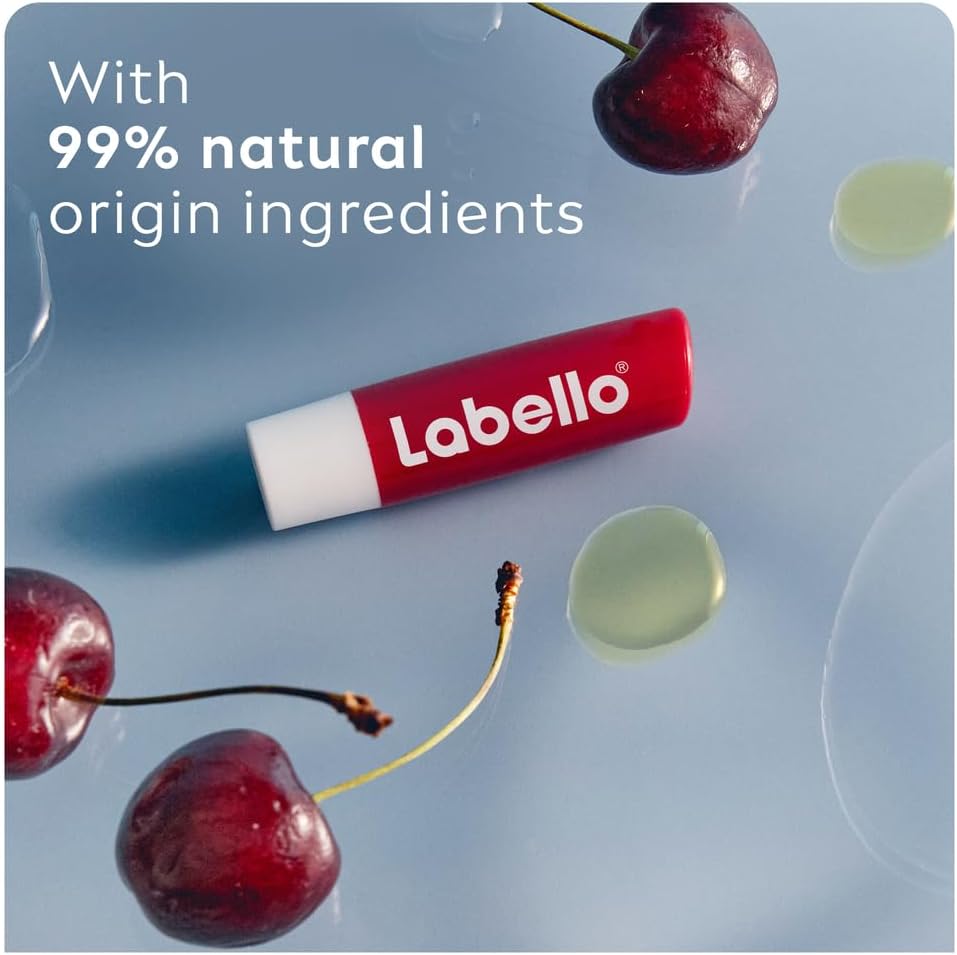 Refect Beauty Labello Shine Cherry lip balm with natural ingredients, surrounded by fresh cherries on a blue surface.