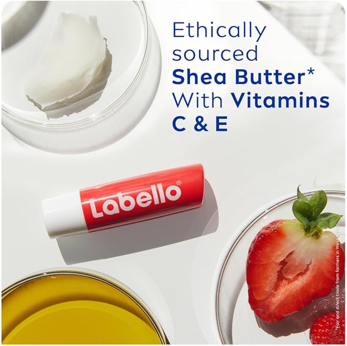 Refect Beauty Labello Strawberry Shine lip balm with shea butter and vitamins C and E on a white surface with fruit.
