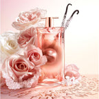 Refect Beauty Lancome Idole Aura perfume bottle surrounded by pink roses and vanilla beans on a soft glowing surface