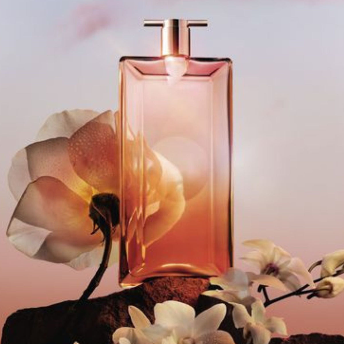 Refect Beauty Lancôme Idôle Now Eau de Parfum bottle with rose and orchid flowers against a soft sunset background